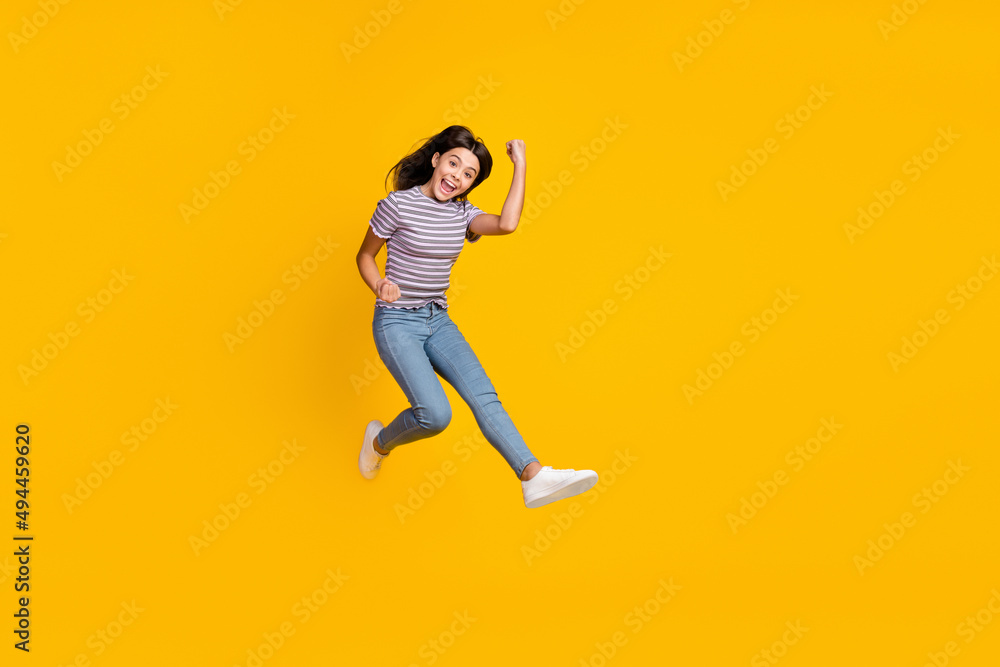 Full size photo of young lady rejoice success fists hands triumph jump isolated over yellow color background
