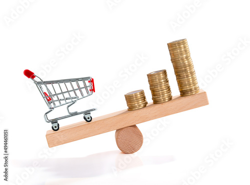 Inflation. Shopping and money. Coin and shopping trolley on wooden seesaw. Supermarket shopping trolley. Concept of growth of food sales, growth of market basket or consumer price index. photo