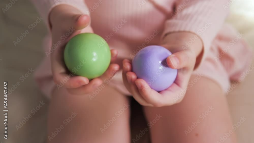 Purple and green egg in the hands of a child. Baby's hands are close-up with Easter eggs. Broken shell Purple and green egg in the hands of a child. Baby's hands are close-up with Easter eggs. Broken shell