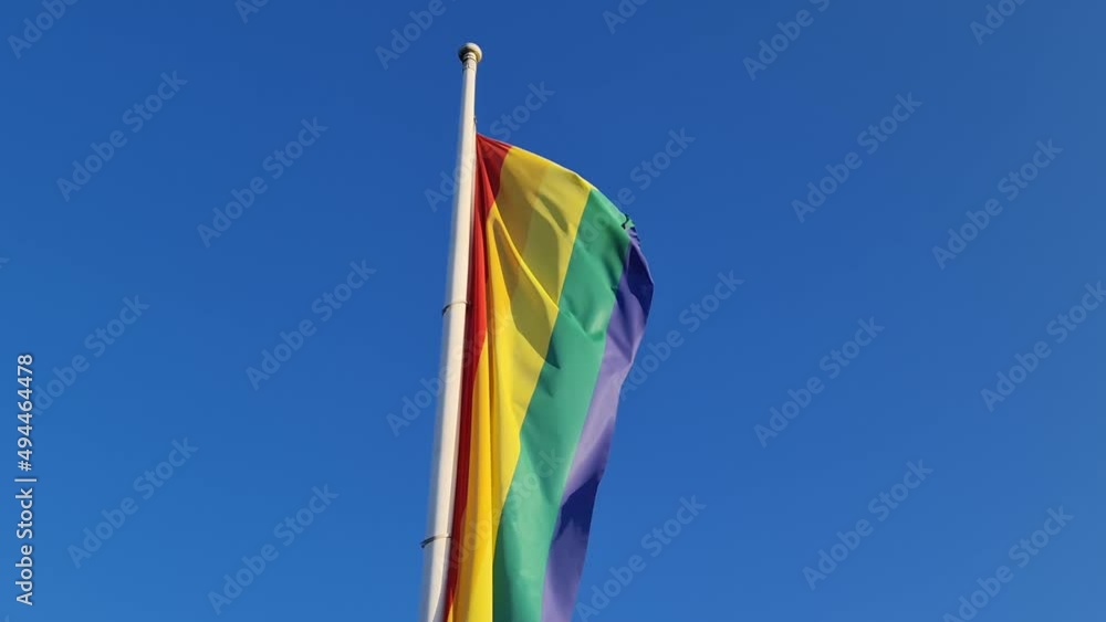 Rainbow pride flag moving in the wind against a blue sky. Lgbt ...