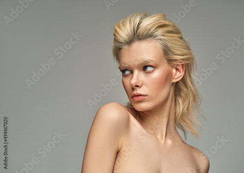 Portrait of sensual blonde woman over gray background with copy space