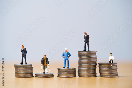 Five Miniature figure in each career standing to different high and low coins stacking for variation of income or salary in each job concept.