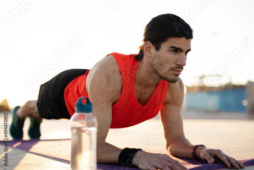 Young muscle man training outside. Fit handsome man doing exercise..