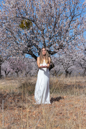 Young and beautiful woman relaxed and meditating in white dress in nature