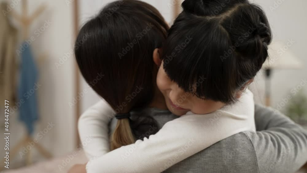 slow motion of sweet asian little girl putting arms around her mom in the living room at home. back view of mother embracing daughter slow motion of sweet asian little girl putting arms around her mom in the living room at home. back view of mother embracing daughter
