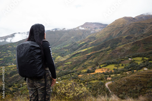 Hermosa foto de una feliz viajera hispana con una mochila en la cima de montañas verdes