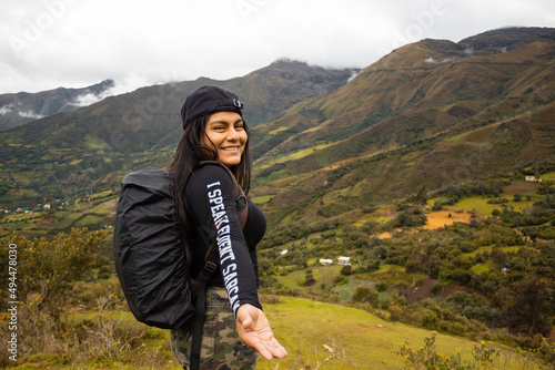 Hermosa foto de una feliz viajera hispana con una mochila en la cima de montañas verdes photo