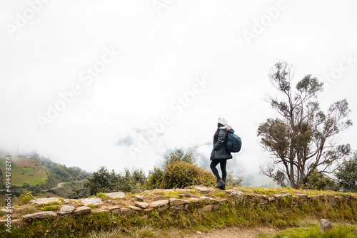 Vista trasera de una mujer con una mochila en una caminata. Mujer joven de pie en un camino disfrutando de la vista panorámica desde la parte superior.