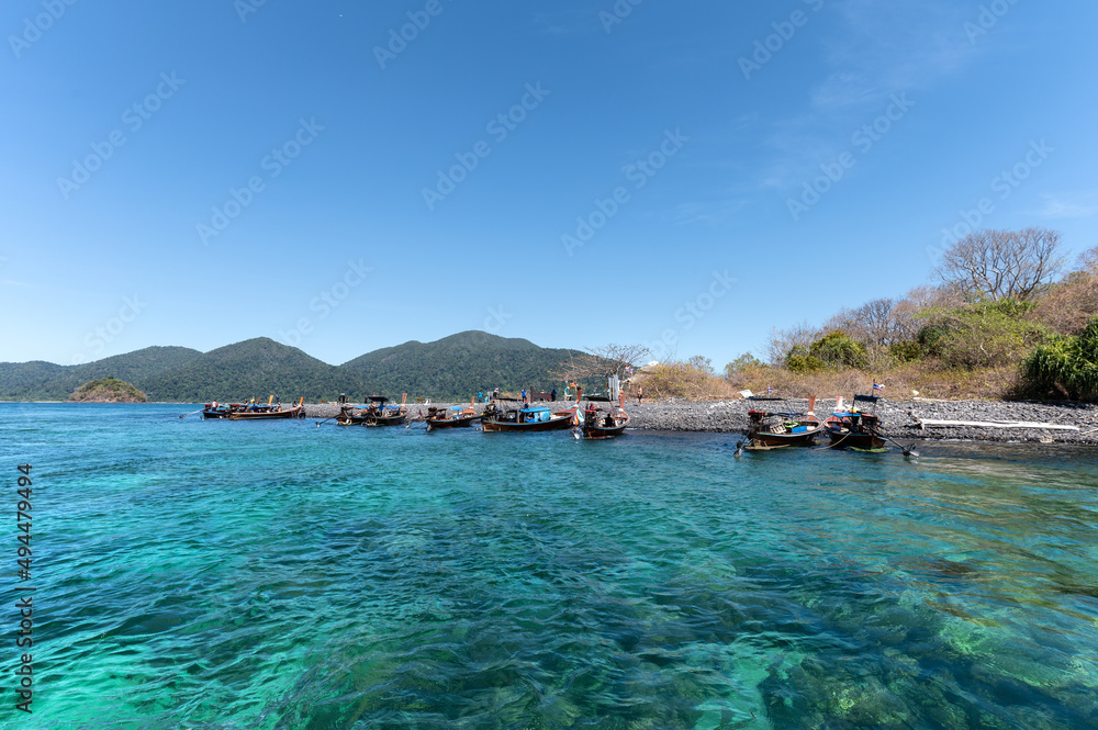 Koh Lipe island with wooden long-tail boat sailing in tropical sea on sunny day