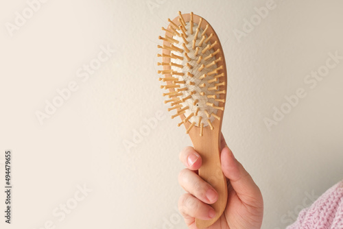 close-up of wooden comb, combing dirty greasy hair with a wooden massage brush. Woman serious hair loss problem for health care shampoo, beauty product concept, haircut care
