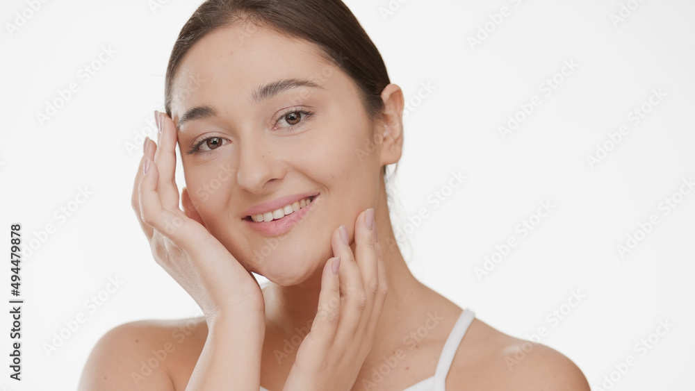 Beautiful Caucasian young plus size woman touches her face looks at camera and smiles widely on white background | Anti aging concept Beautiful Caucasian young plus size woman touches her face looks at camera and smiles widely on white background | Anti aging concept