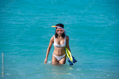 Sexy Asian woman wearing white swimming suite holding snorkel equipment flippers and snorkeling mask on the sea recreation sport summer holiday concept.