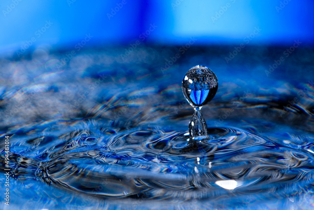 Macro shot shallow focus shot of a drop falling on detal blue wavy water - obrazy, fototapety, plakaty 