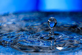 Macro shot shallow focus shot of a drop falling on detal blue wavy water