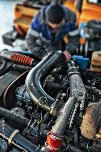 Automobile locksmith or mechanic repairs engine of truck in workshop. Car maintenance. Car service. Background. © SerPak