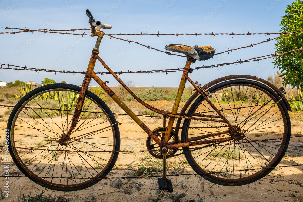 Old rusty bicycle hanging on barbed wire in Farol Island, Portugal