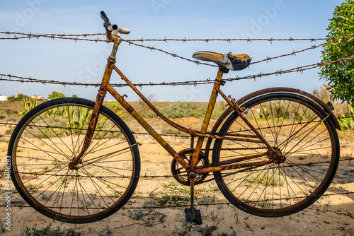 Old rusty bicycle hanging on barbed wire in Farol Island, Portugal