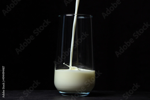 Glass of milk on a black background. Milk is poured into a transparent glass. natural healthy drink