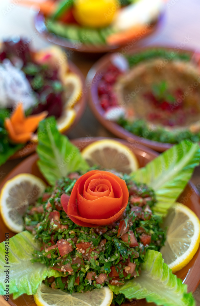 Multiple lebanese appetizers and salads together on the table. focused on tabbouleh