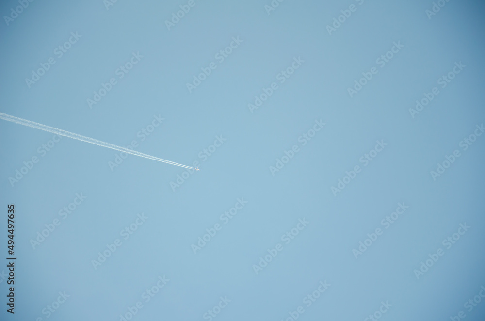 A passenger plane flies across the blue sky and leaves a white path. A passenger plane flies across the blue sky and leaves a white path.