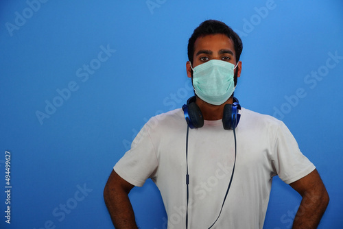 Portrait of happy young man with surgical medical mask in white t- shirt standing with victory  photo