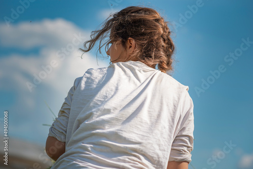 Portrait of a young beautiful girl in a white T-shirt against the sky.