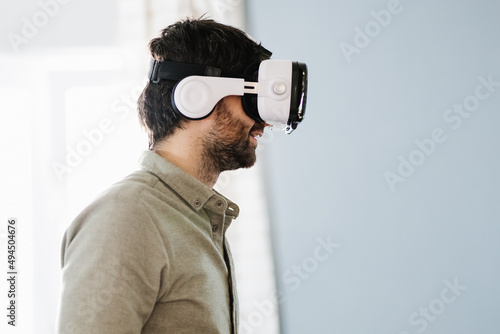 Serious ethnic man wearing VR goggles and looking away photo