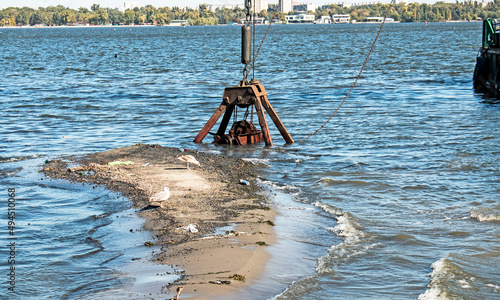 The bucket of a special dredger cleans the artificial island. Ecological disaster in the coastal waters of the Dnieper River