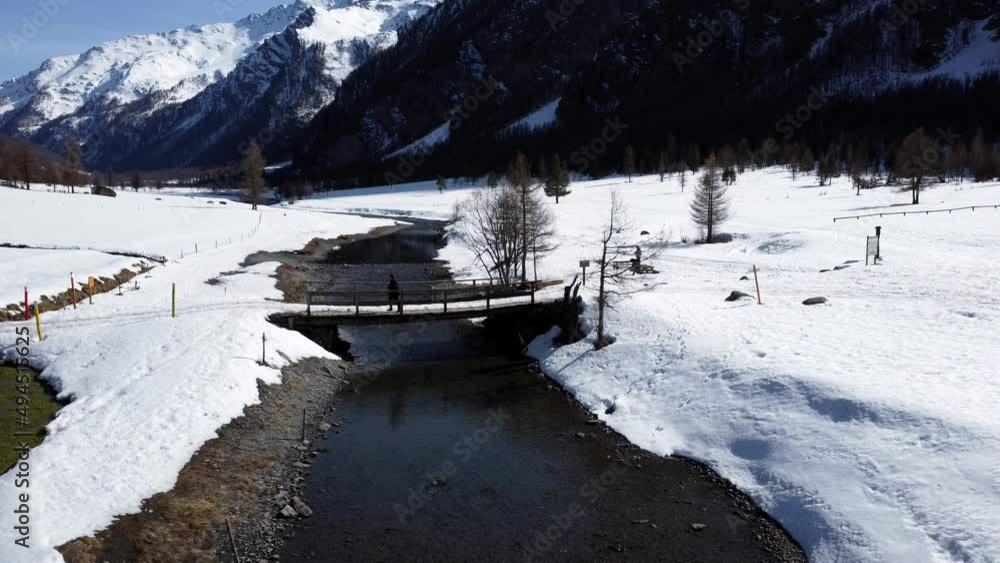 Aerial view man walks on wooden bridge in mountain landscape. Video 4K Aerial view man walks on wooden bridge in mountain landscape. Video 4K