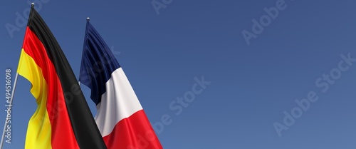 Flags of Germany and France on flagpoles on side. Flags on a blue background. Place for text. Berlin, Munich. Paris, Europe. Commonwealth. 3D illustration.