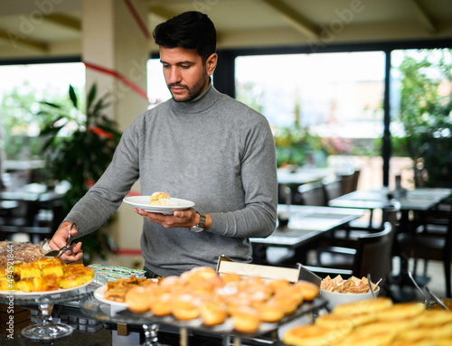 Man picking food at a buffet in a hotel for his breakfast