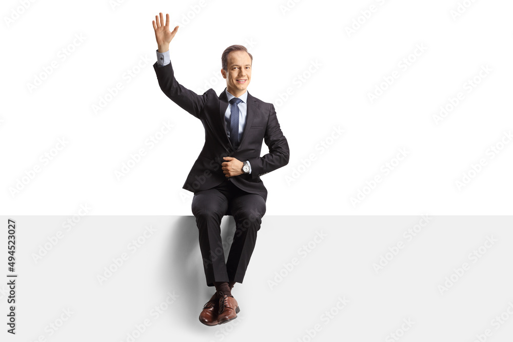 Professional man in suit and tie sitting on a blank panel and waving Professional man in suit and tie sitting on a blank panel and waving