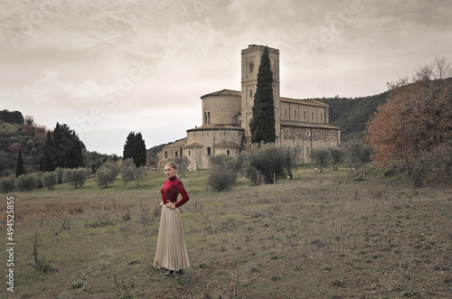 фотографія young woman in front of the abbey of sant'antimo, tuscany, italy