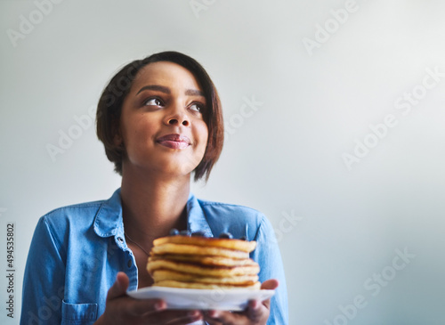 This takes me back to my childhood. Shot of an attractive young woman eating delicious pancakes at home.