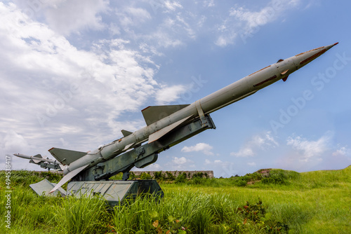 Combat tactical medium-range missile in the grass against a blue sky with white clouds on a clear summer day