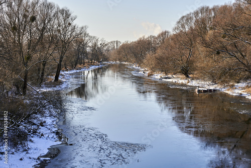 Wda frozen river next to leafless trees. photo
