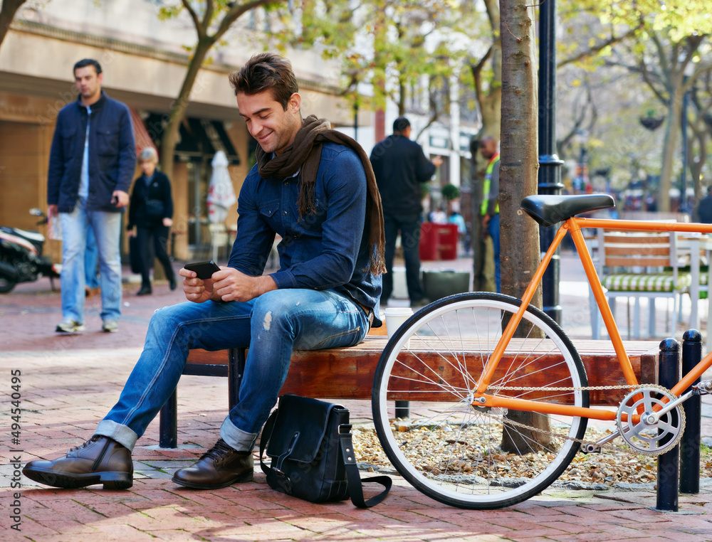 Enjoying city life. Shot of a man using his cellphone while taking a break in the city with his bicycle beside him. Enjoying city life. Shot of a man using his cellphone while taking a break in the city with his bicycle beside him.