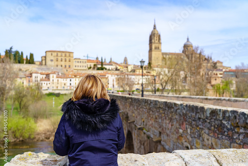 Woman observing the city of Salamanca from the bank of the Tormes river over the Roman bridge.