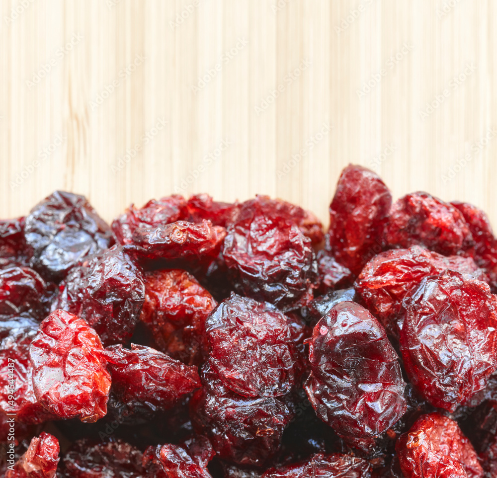 Close up picture of dried cranberries on a wooden background, selective focus. Close up picture of dried cranberries on a wooden background, selective focus.