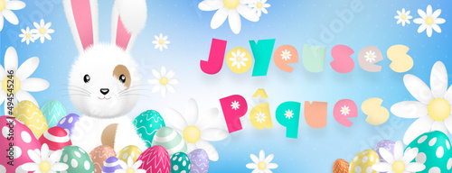 Texte «Joyeuses Pâques» aux couleurs pastels, avec un mignon lapin blanc derriere des oeufs colorés et des fleurs sur un fond bleu
