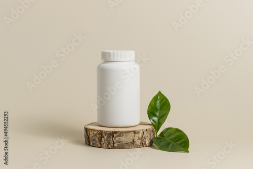 Photography White mockup medical bottle of pills or vitamins on wooden stand with green leaf