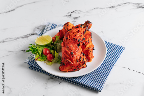 indian culture Tandoori chicken with lime in a dish isolated on napkin side view on grey background