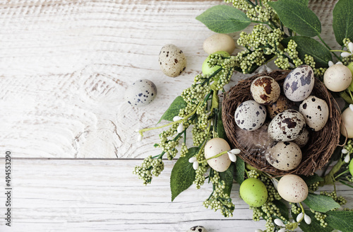 green wreath with easter quail eggs and flowers on wooden background