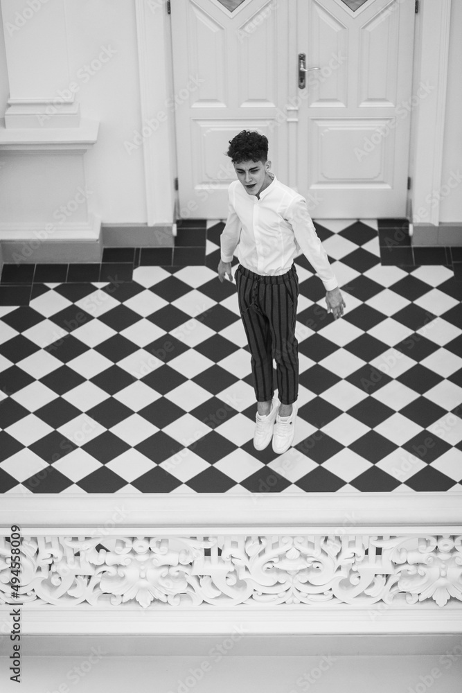 Young charismatic dancer jumping in a museum. Black and white photo. Vertical view. Young charismatic dancer jumping in a museum. Black and white photo. Vertical view.