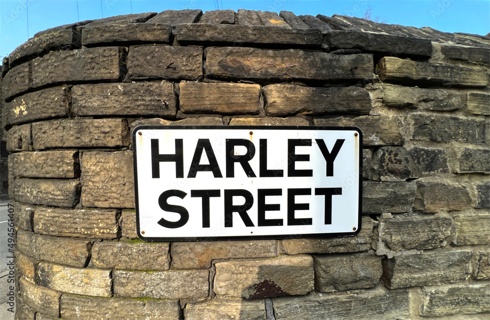 Fototapeta premium Harley Street road sign, affixed to an old stone wall, in the post industrial town of, Brighouse, UK