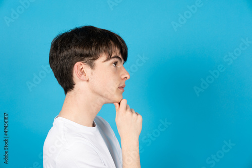 Side view of boy thinking and looking to blue copy space