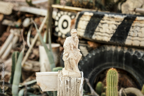 Small statue amongst the junk in the middle of the desert in Coober Pedy, South Australia photo