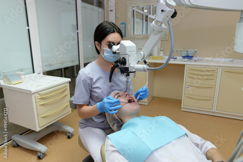 woman dentist treats patient s teeth under microscope
