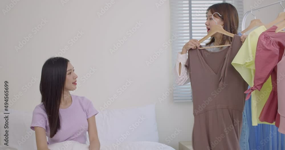 Slow motion of two young Asian women are having fun trying on hanging clothes.Women's relaxation by trying on the outfits they bought. Slow motion of two young Asian women are having fun trying on hanging clothes.Women's relaxation by trying on the outfits they bought.