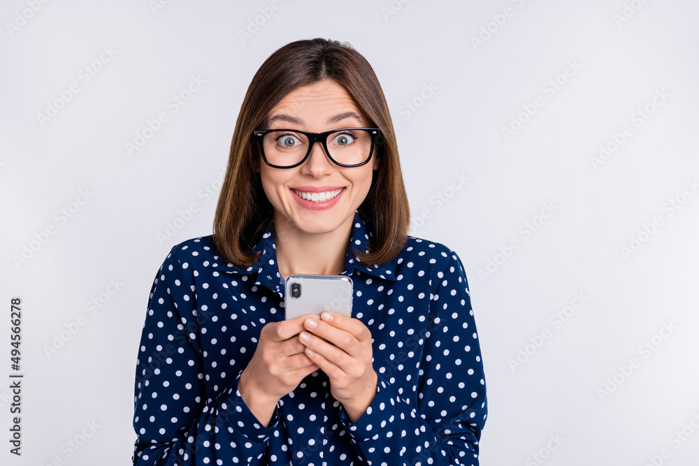 Photo of cheerful excited lady hold telephone enjoy feedback wear dotted blouse isolated grey color background Photo of cheerful excited lady hold telephone enjoy feedback wear dotted blouse isolated grey color background